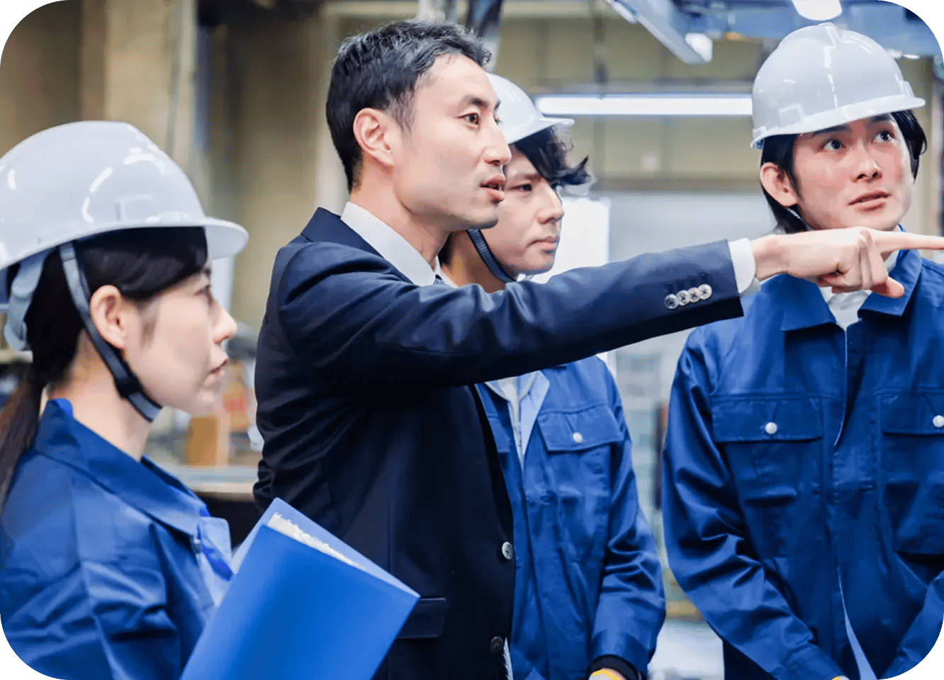 ヘルメットを着用した作業員と担当者が、工事現場で方向を確認しながら打ち合わせをしている様子