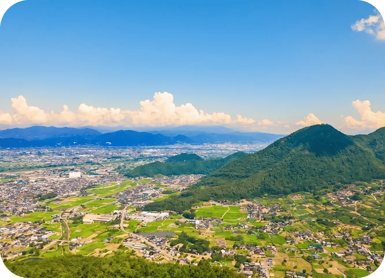 青空の下で山と市街地が広がる、自然豊かな地方都市の風景