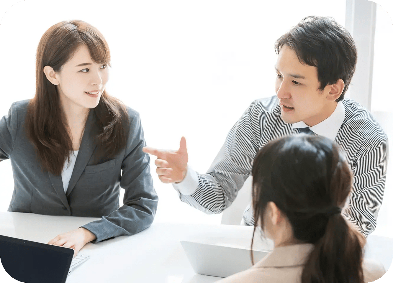オフィスで男女の社員が着席しながら、仕事の内容について打ち合わせをしている様子